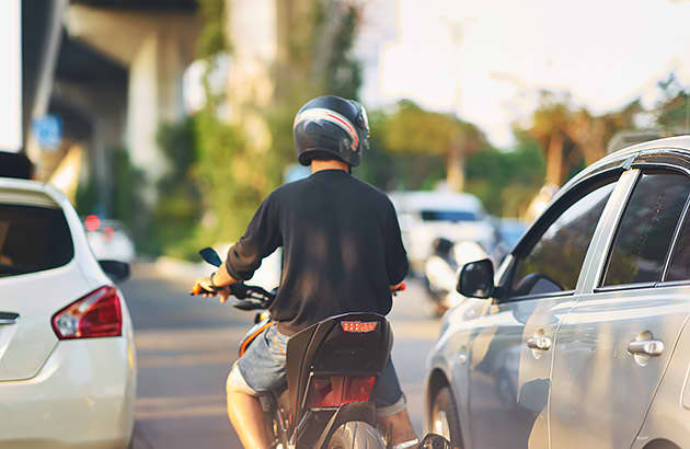 A motorcyclist riding between cars
