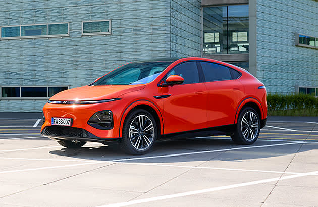 A red Xpeng G6 parked in front of a modern building