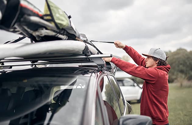 A man is checking the strapping on his loaded roof rack