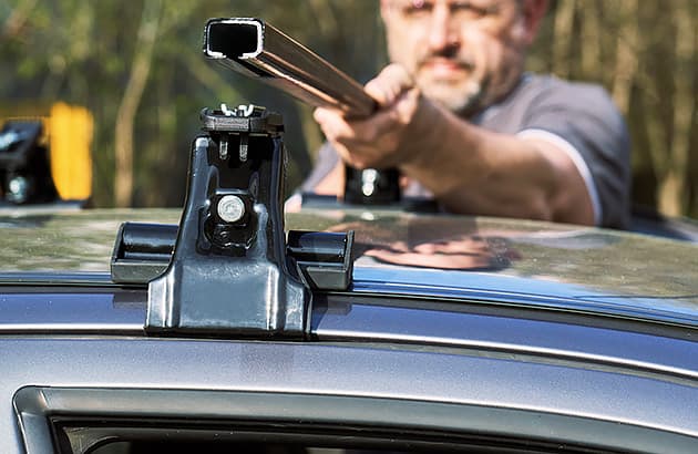 A man is fitting a roof rack to his car