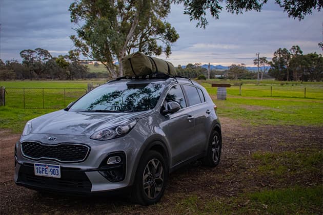A Kia Sportage with a swag tent stored and tied to the roof
