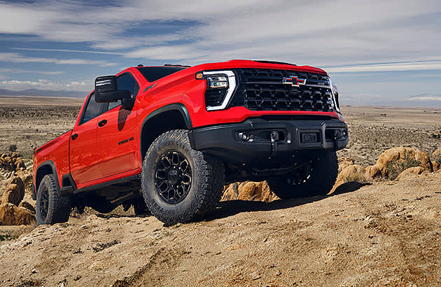 A red Chevrolet Silverado climbing a steep sand hill