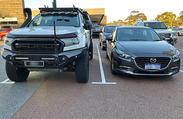 A Ford Range parked next to a smaller Mazda 3