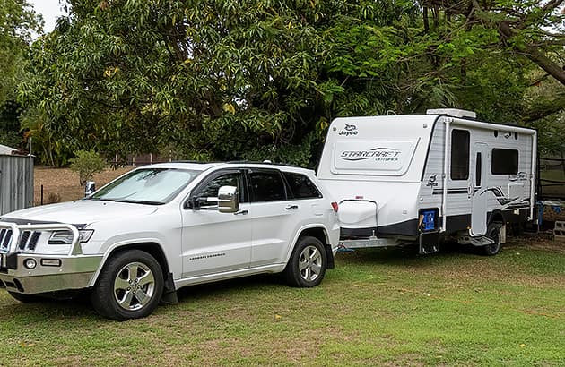 A caravan hitched to a white four-wheel drive in the yard of a home