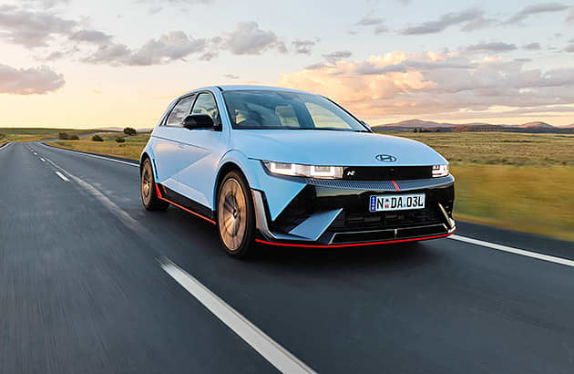 A blue Hyundai Ioniq 5 driving on a country road