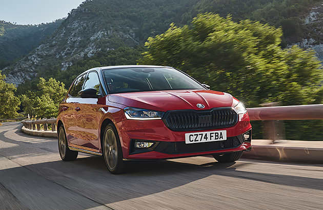 A red Skoda Fabia driving along a country road