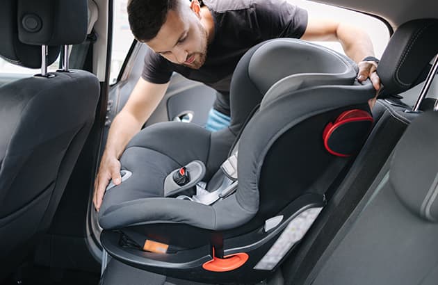 A man installing a childs' seat in a car