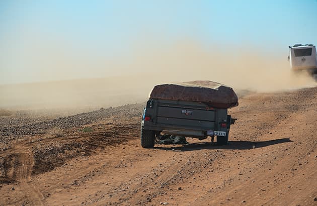 A caravan stranded on the side of the road with a missing wheel