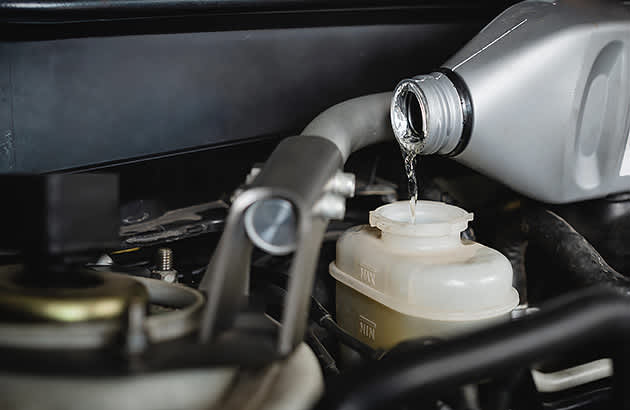 A close up of brake fluid being poured into a brake fluid reservoir