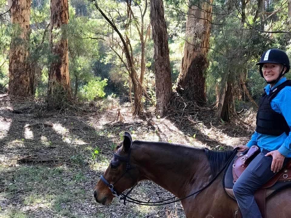 Julie Townsend is riding her horse, smiling