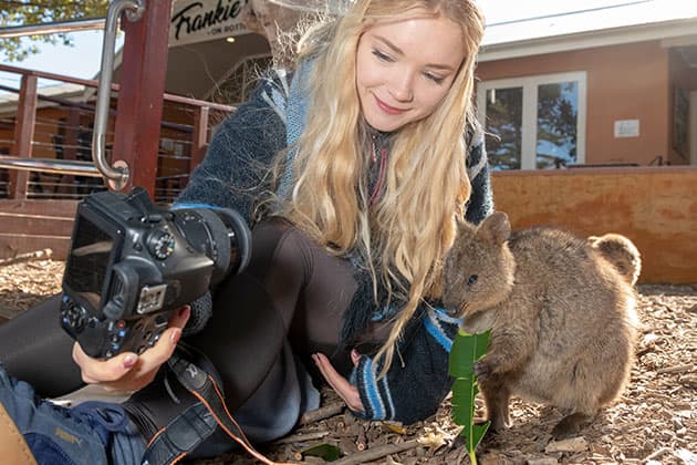 A young girl taking a selfie with a quokka