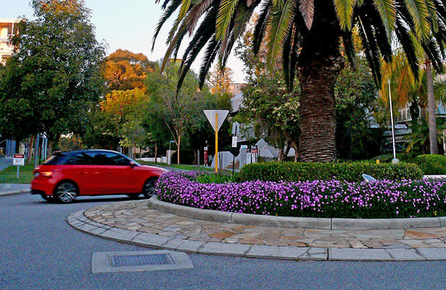 A red car travels through a roundabout