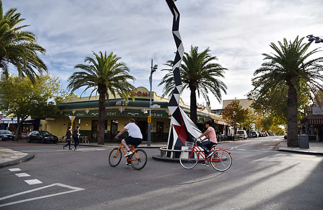 Two cyclists travel through a Perth roundabout