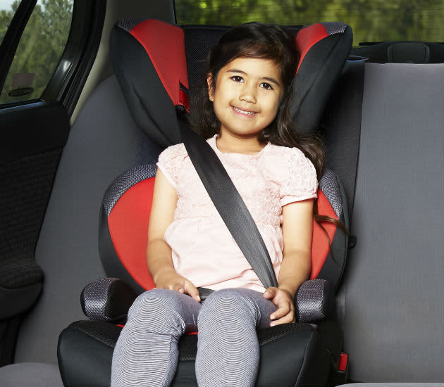A  four year old girl in a booster seat
