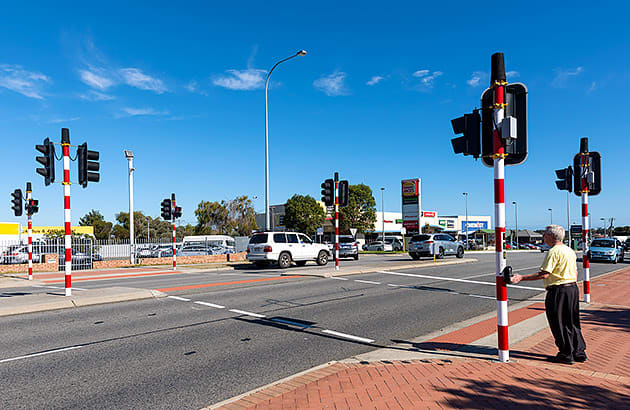 A man in waiting to cross the road at a pelican crossing