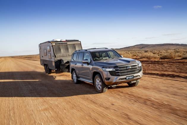 Silver Toyota Landcruiser 300 Series towing a caravan on dirt road