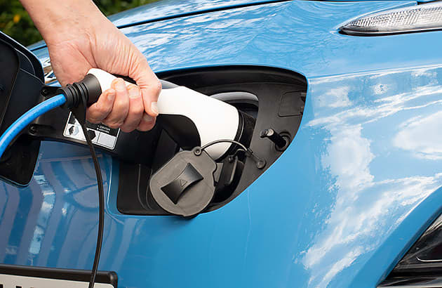 A close up of a person plugging their EV in to charge