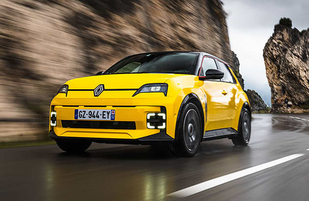 A yellow Renault 5-E-Tech on a winding mountainous road