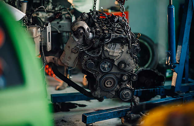 A car engine being lifted by a small hoist
