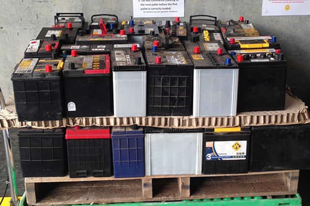 Stack of old car batteries on a wooden pallet
