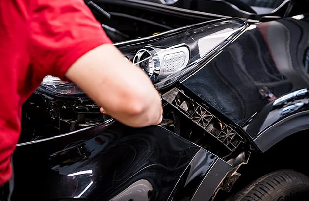 A man works on a car bumper bar