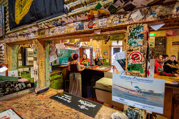 A woman is standing at the bar inside of an old-school tavern.