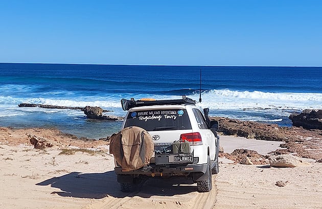 A white four-wheel drive parked on a beach