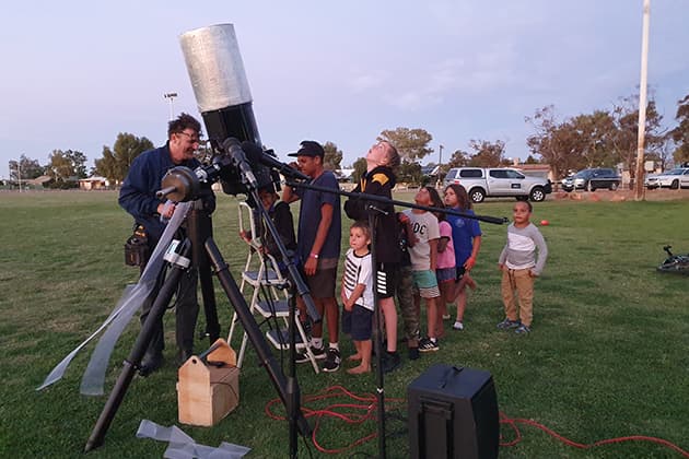 Children line up to look through a telescope