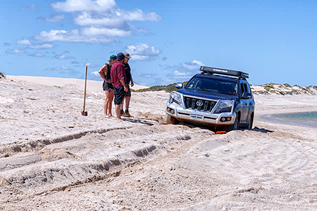 Men assessing bogged car