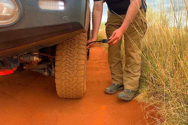 Man changing tyre pressure on 4WD