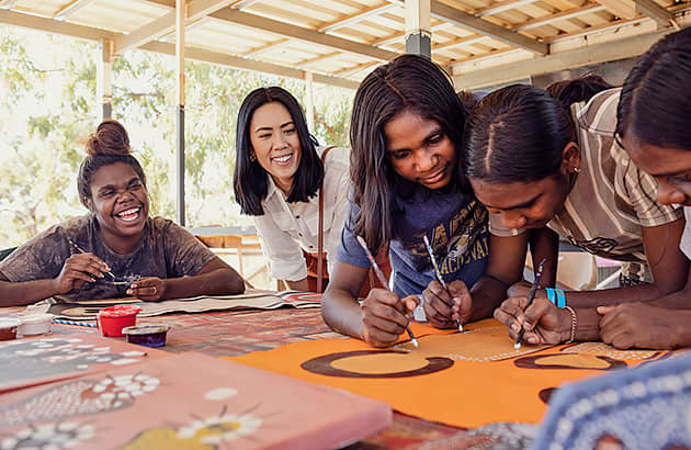 A woman watches Aboriginal artists as they paint