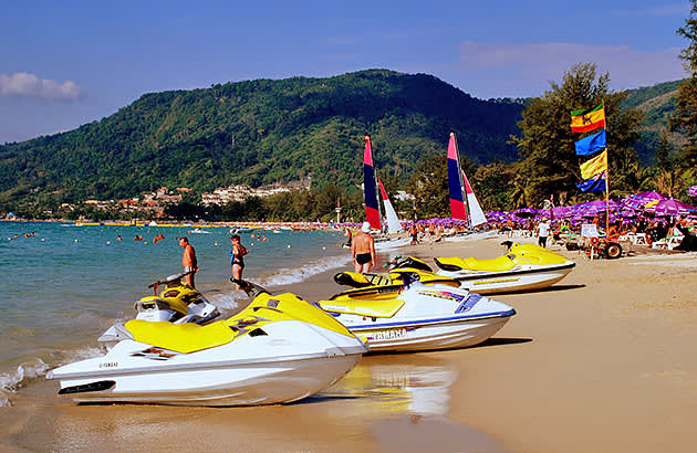 A row of yellow and white jet skis on a beach