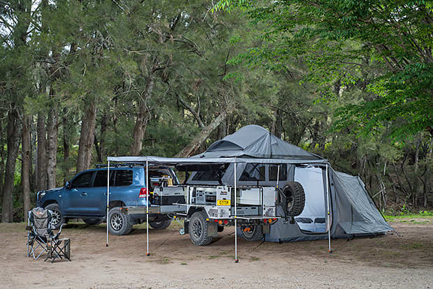 A softfloor camper trailer is set up in bushland