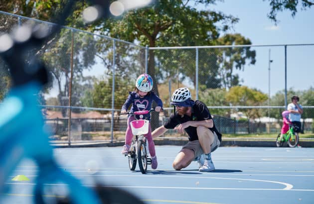 Instructor teaching child to ride a bike