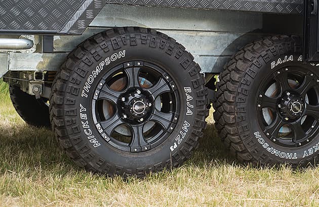 A close up of the wheels of a silver dual-axle trailer