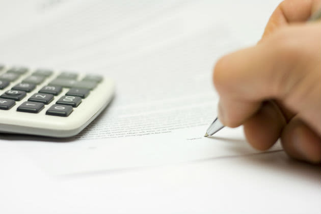 Signing paperwork with a calculator nearby