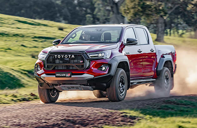 A red Toyota Hilux on a gravel country road