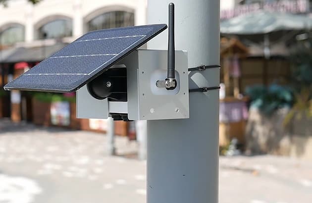 An air pollution sensor strapped to a pole in a city street