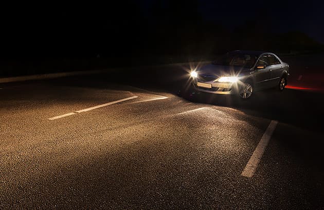 A car on a country road at night changing lanes