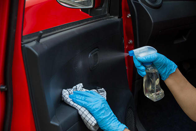 Spray cleaning solution onto inside of car door
