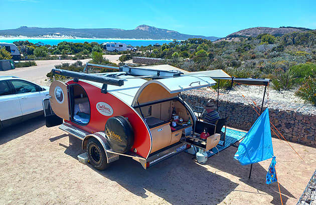 A teardrop camper set-up at a beachside campsite