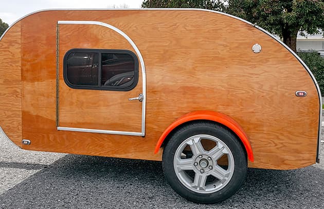 A side view of a wooden teardrop camper