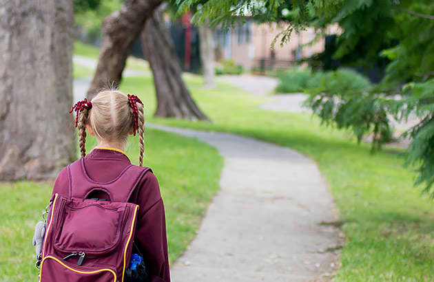 A young girl in school uniform walking on a path