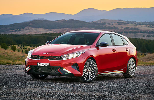 A red Kia Cerato in a mountainous landscape