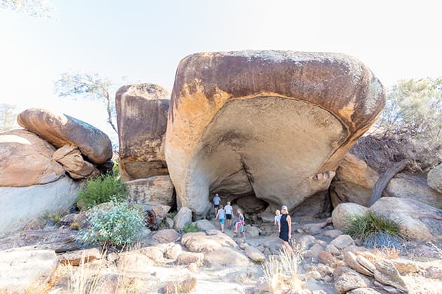 People are walking underneath a large rock face