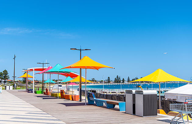 A walkway close to the beach with colourful umbrellas