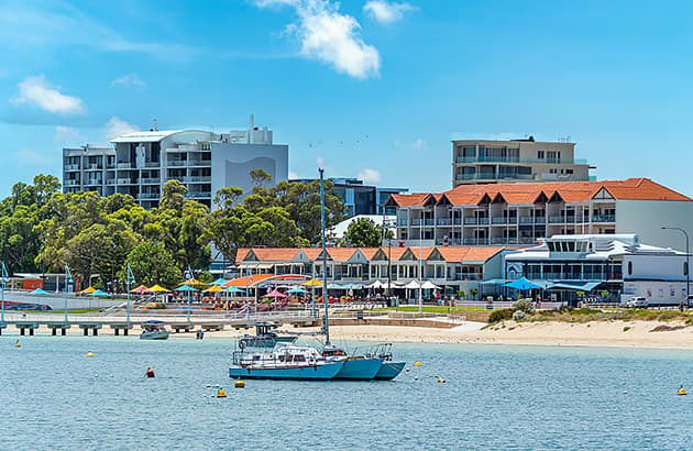 A beach viewed from the water with a jetty and a boat near it