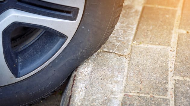 car tyre squished against concrete kerb