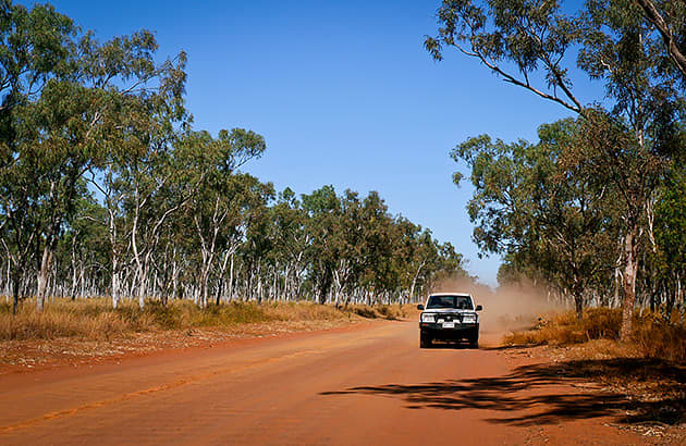 A 4WD travelling down red dirt road