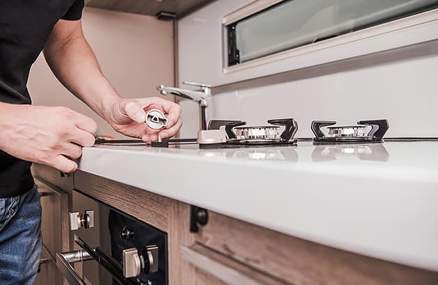 A man inspecting a cooktop in a caravan